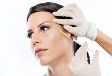 Portrait of beautiful young woman getting botox cosmetic injection in her face over white background.